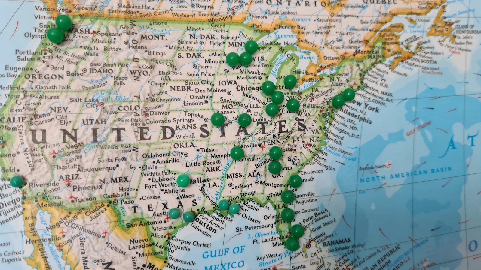 A wall map of the United States dotted with green pins.