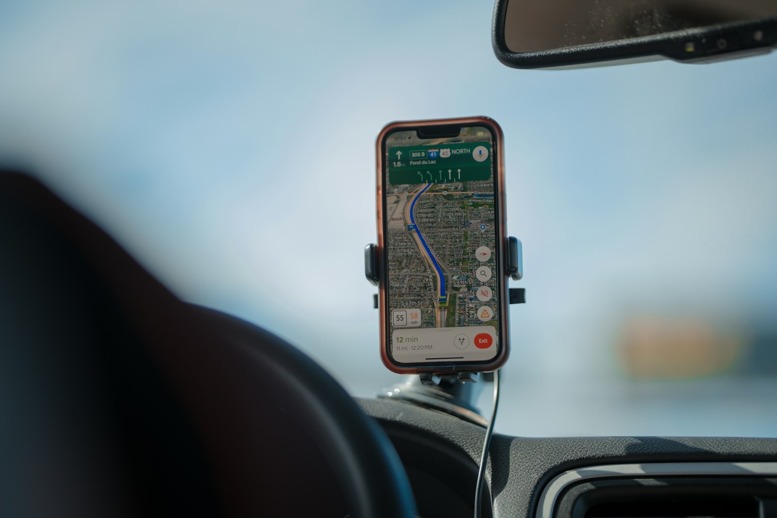 A phone in a dashboard mount showing a route on a map.