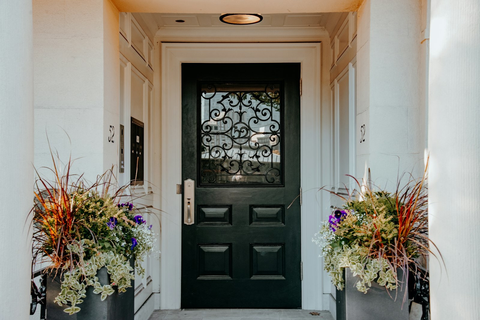 A black front door with a planter of flowers on either side.