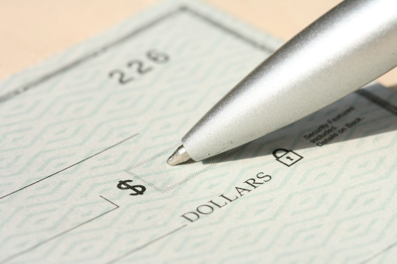 The tip of a pen resting on a blank check.