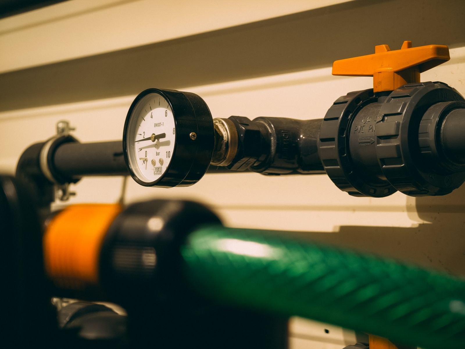 A pressure gauge on a plumbing line next to a ball valve.