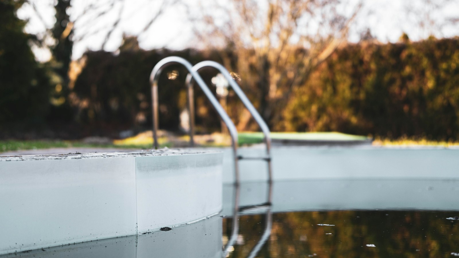 A pool ladder and coping, with the water sitting well below the edge.