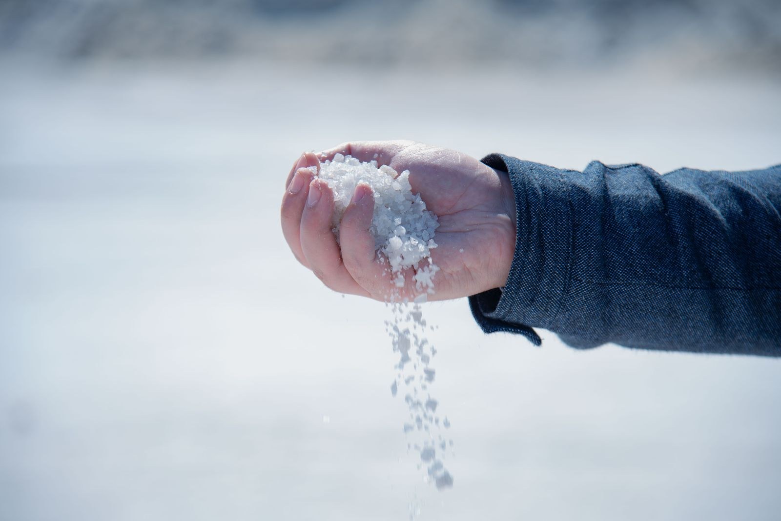 A hand pouring out coarse white salt.