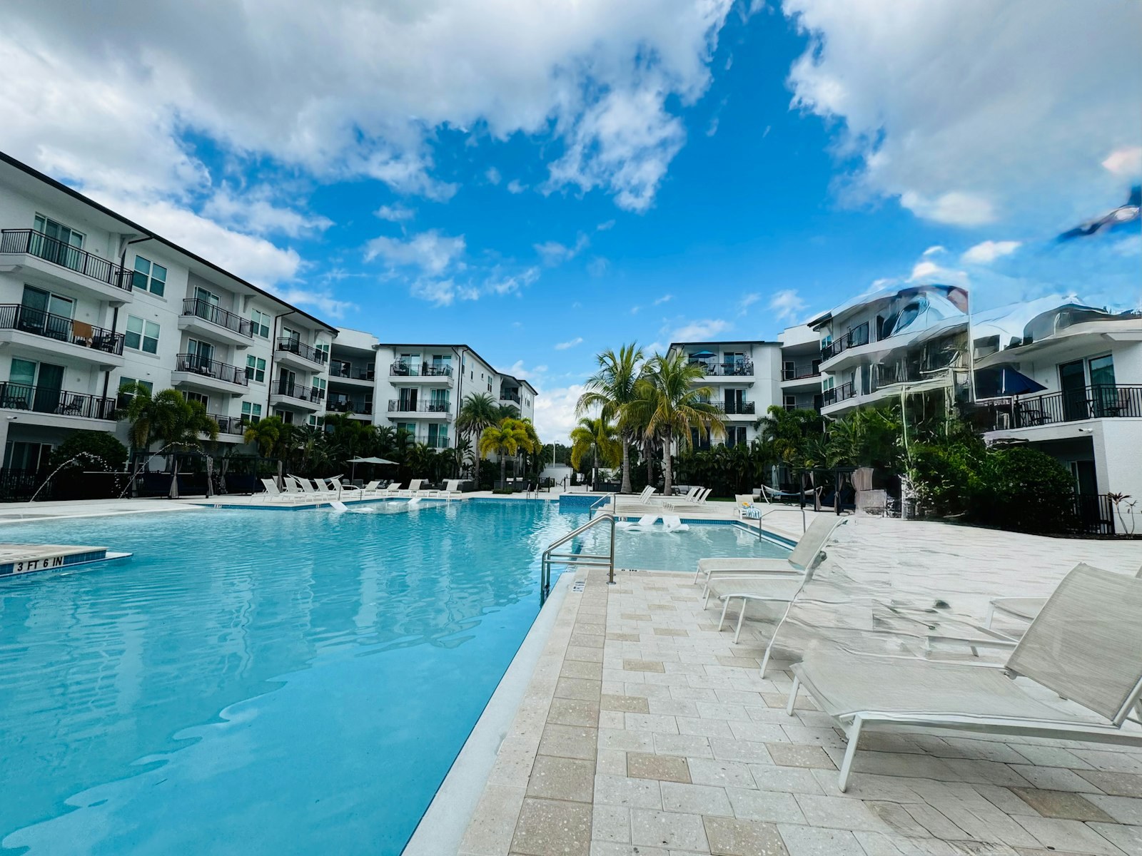 A large pool lined with loungers, with balconied buildings on three sides.