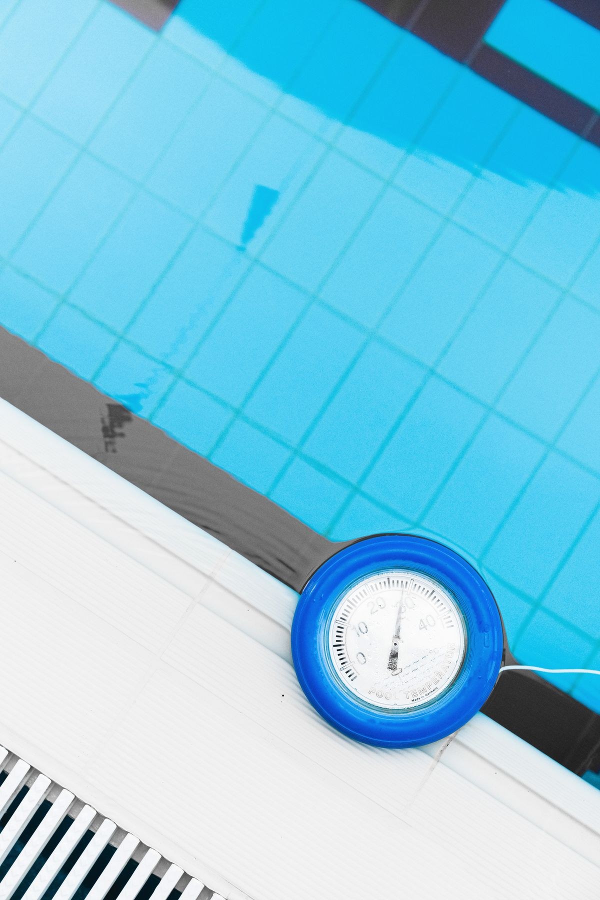 A thermometer floating at the edge of a swimming pool.