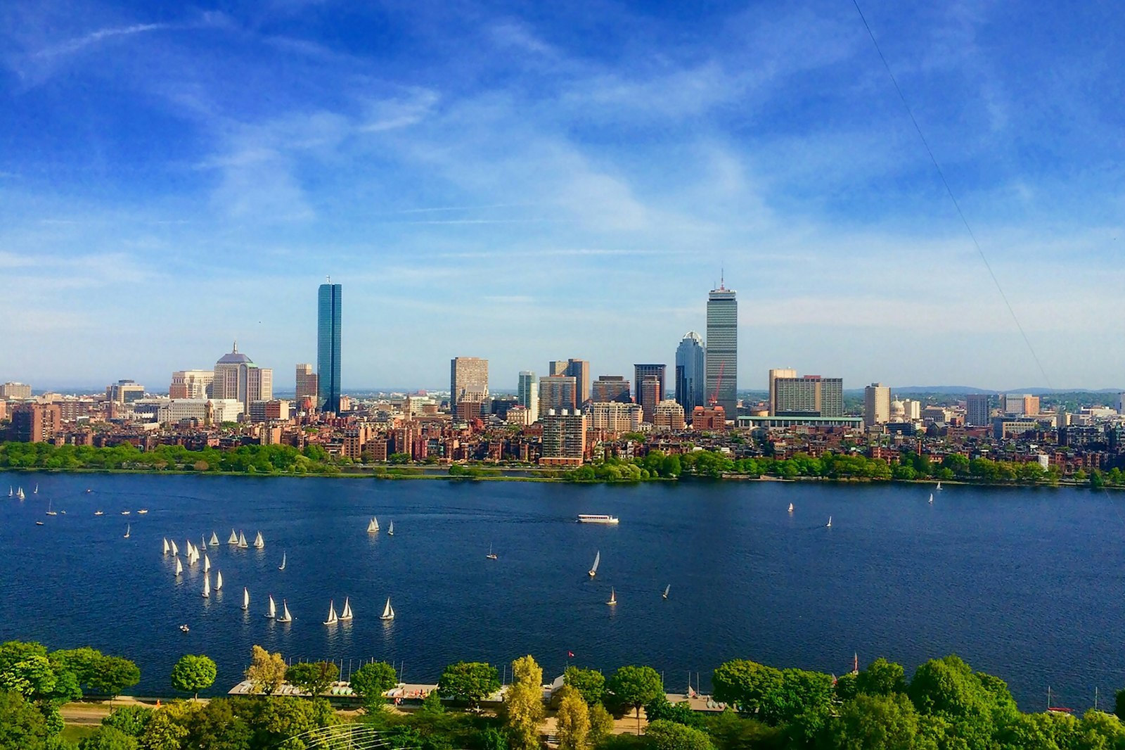 Boston's Back Bay skyline across the Charles River, dotted with sailboats.