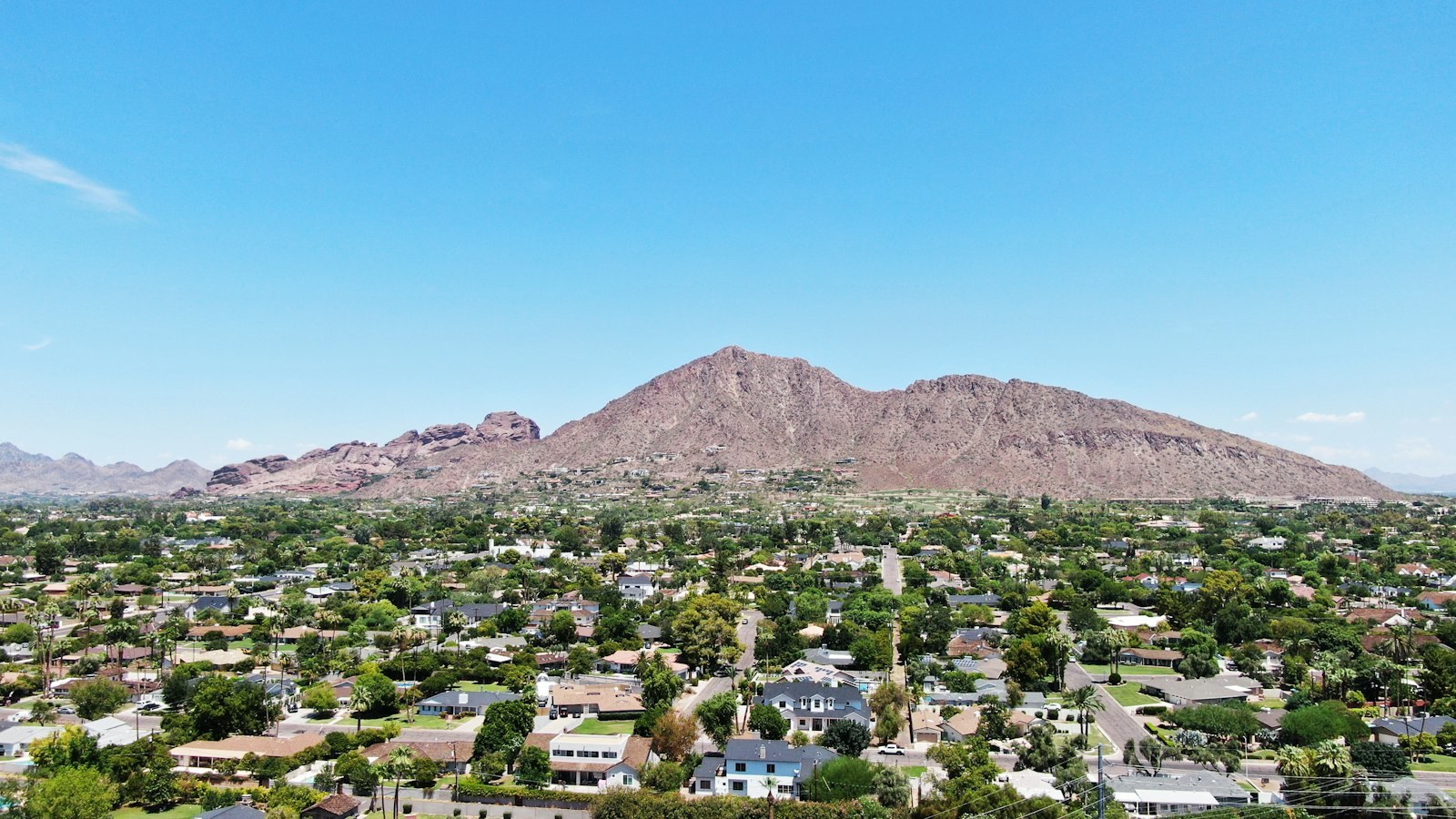 Camelback Mountain rising over a Phoenix neighborhood under a clear blue sky.